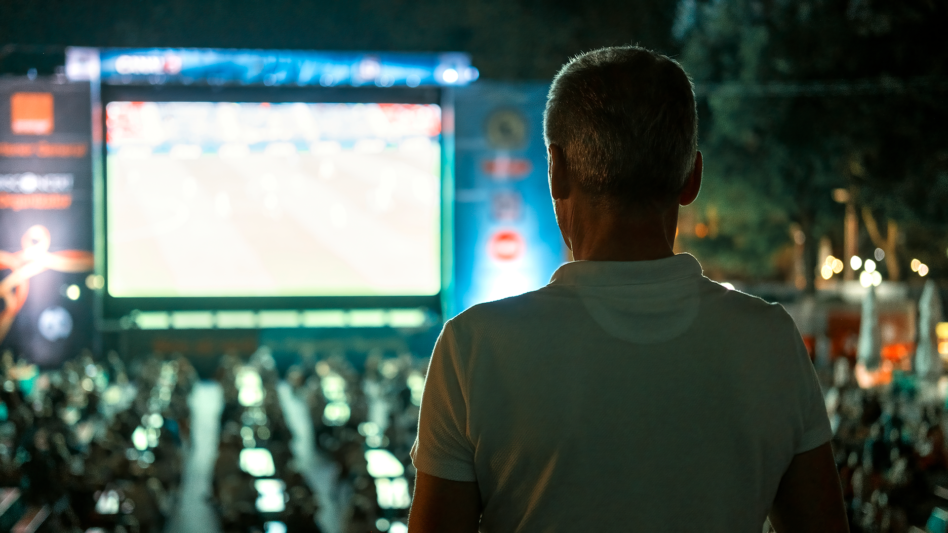 sitting-man-watching-football-public-place-night